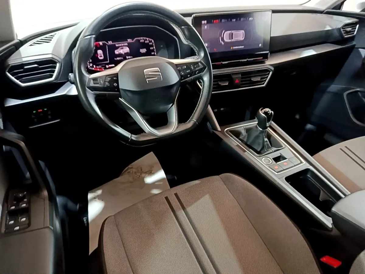 Vue intérieure côté conducteur du tableau de bord et console centrale de la SEAT LEON 1.0 TSI 110 S&S Business 2023 en gris foncé.