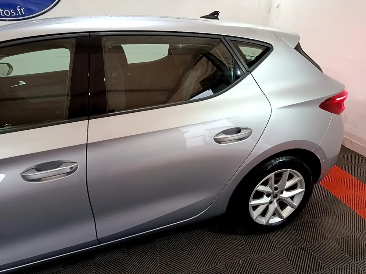Vue latérale droite sur l'arrière d'une SEAT LEON gris foncé avec jante alliage et feux arrière allumés.