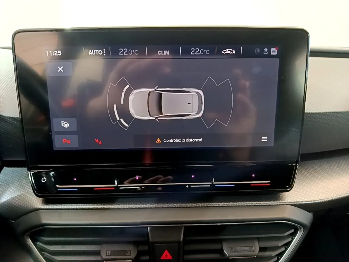 Écran tactile central du tableau de bord montrant l'aide au stationnement d'une SEAT Leon gris foncé.