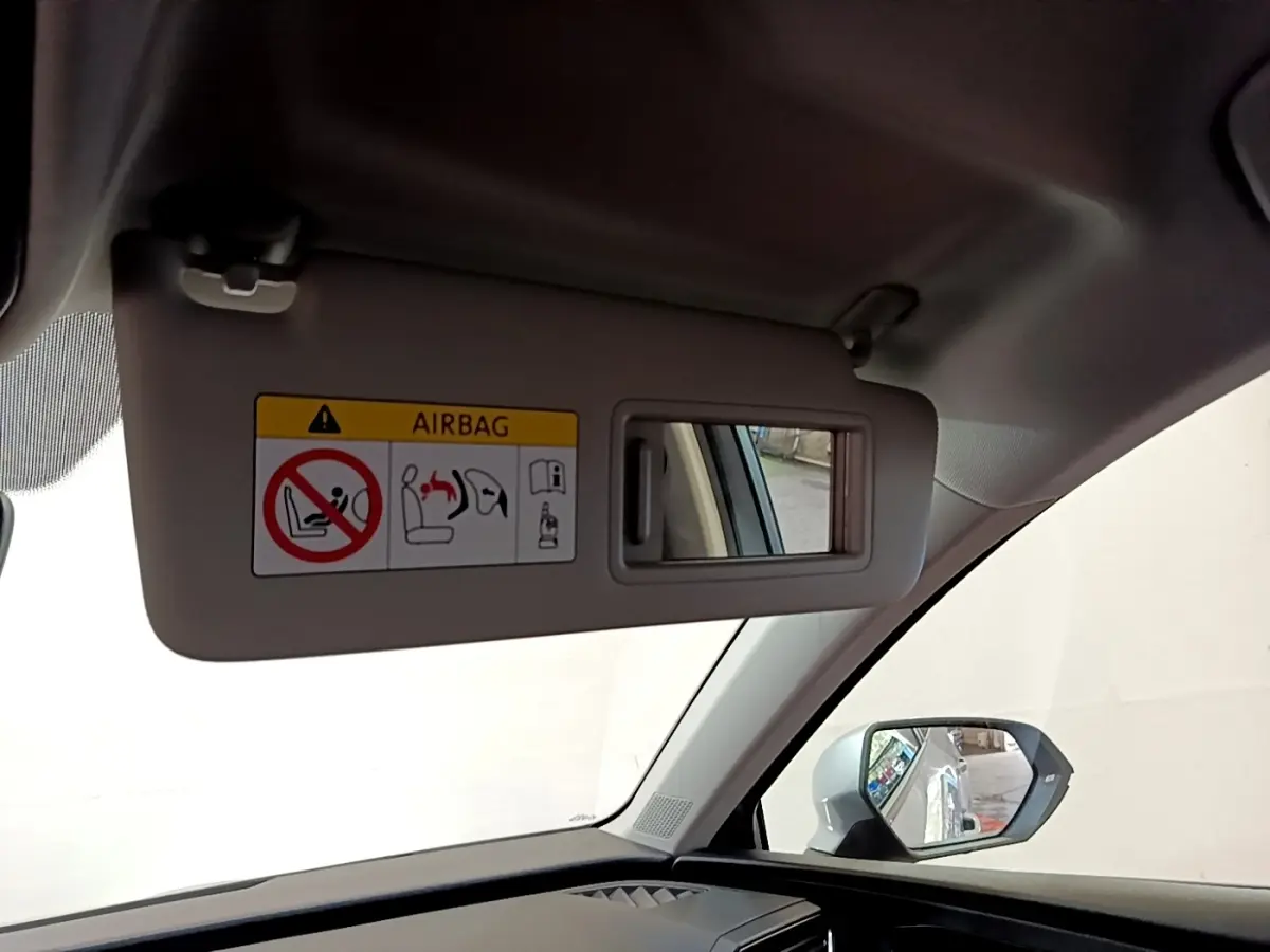 Détail du pare-soleil côté conducteur avec miroir et avertissement airbag dans un SEAT Leon gris foncé 2023.