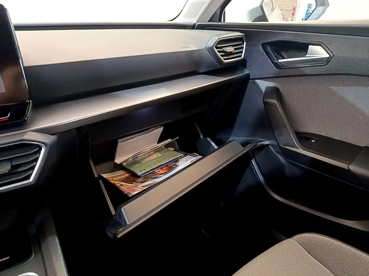 Intérieur côté passager du SEAT Leon 2023 avec boîte à gants ouverte et tableau de bord gris foncé.