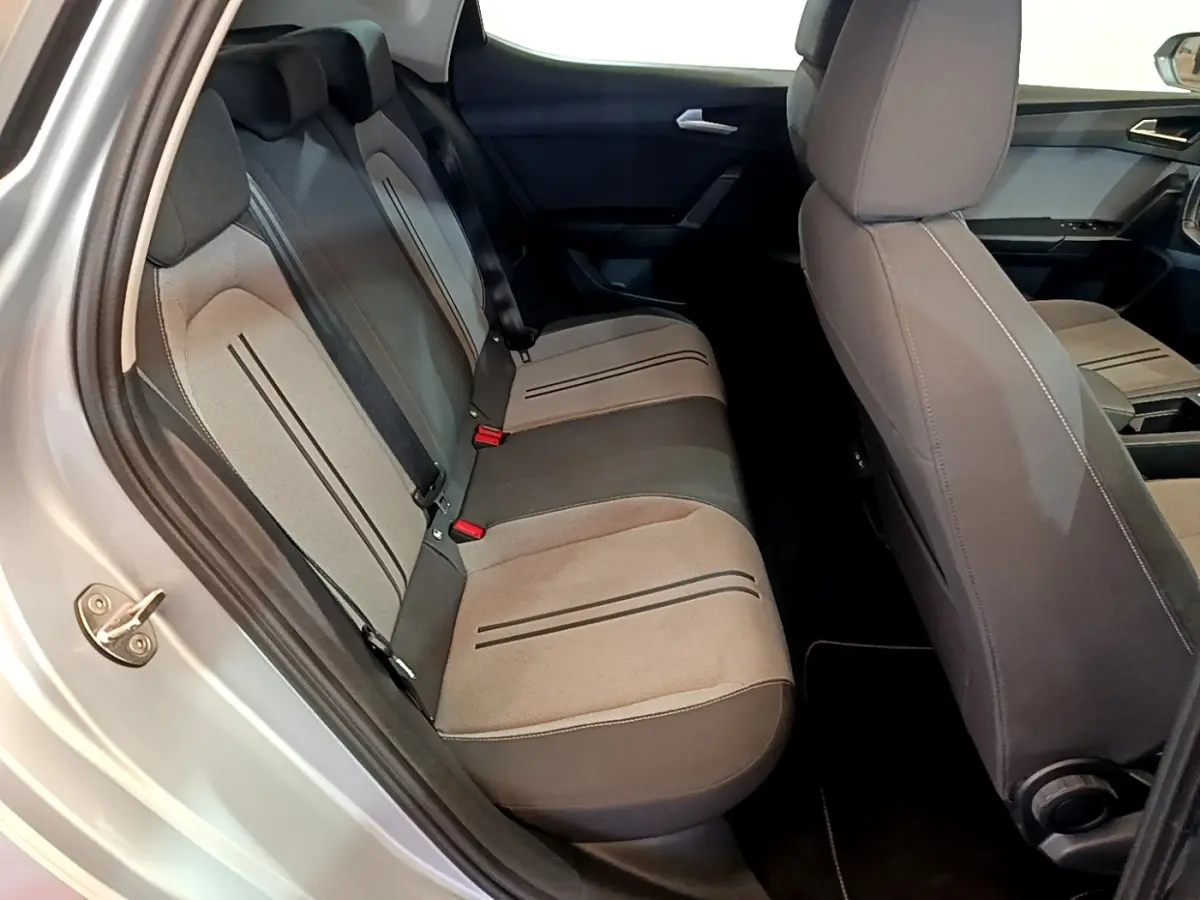 Vue intérieure côté gauche montrant la banquette arrière grise et les sièges avant du SEAT LEON 1.0 TSI 2023.