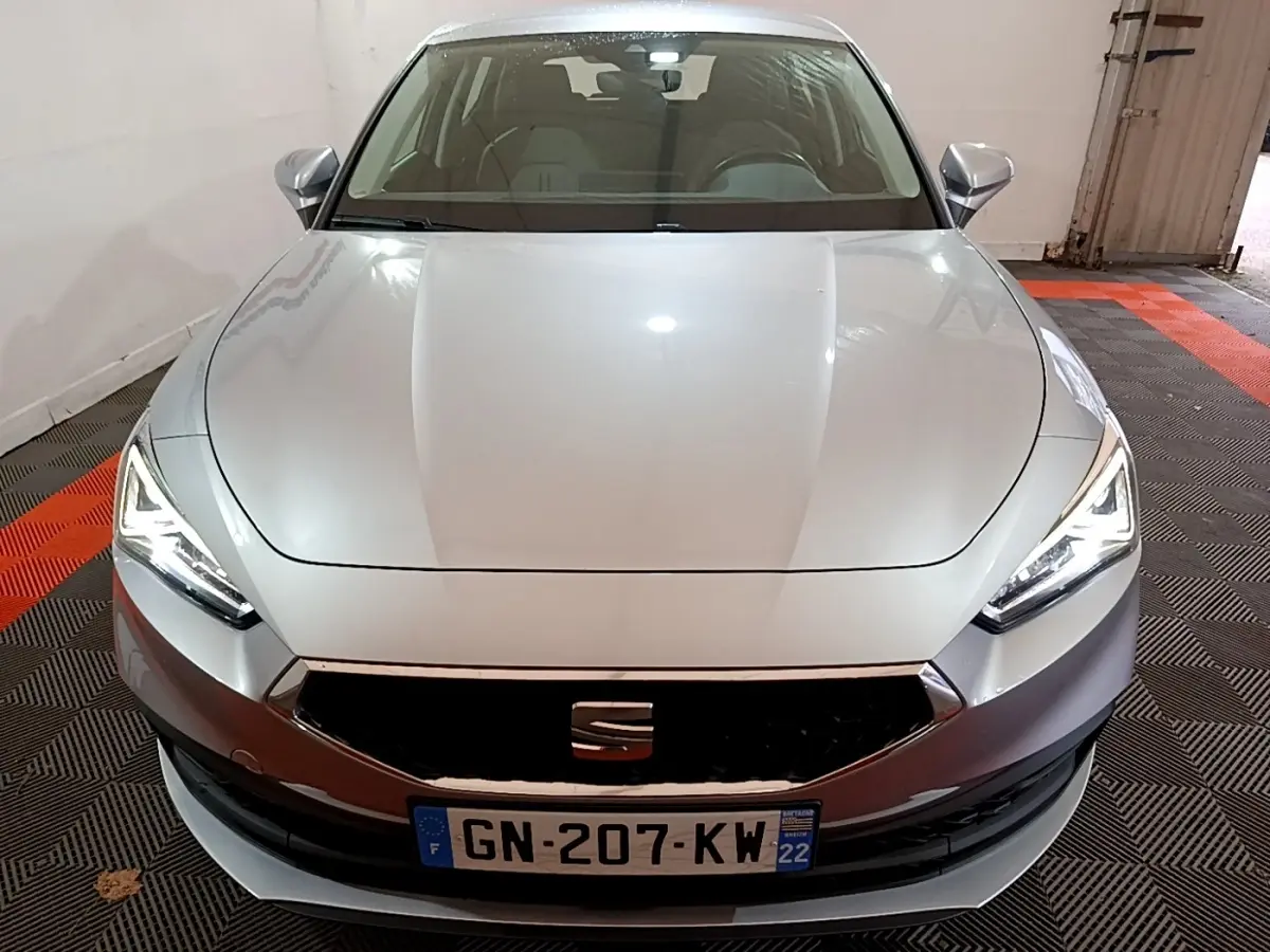 Vue frontale d'une SEAT LEON gris foncé avec phares LED allumés dans un garage fermé.