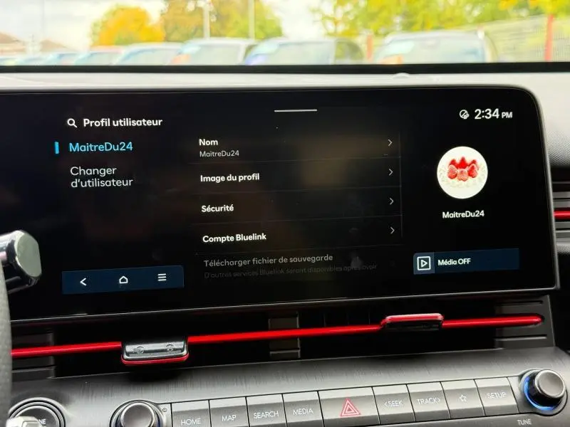 Écran tactile intérieur du Hyundai Kona 2025 avec interface utilisateur et bandeau décoratif rouge sous l'écran.
