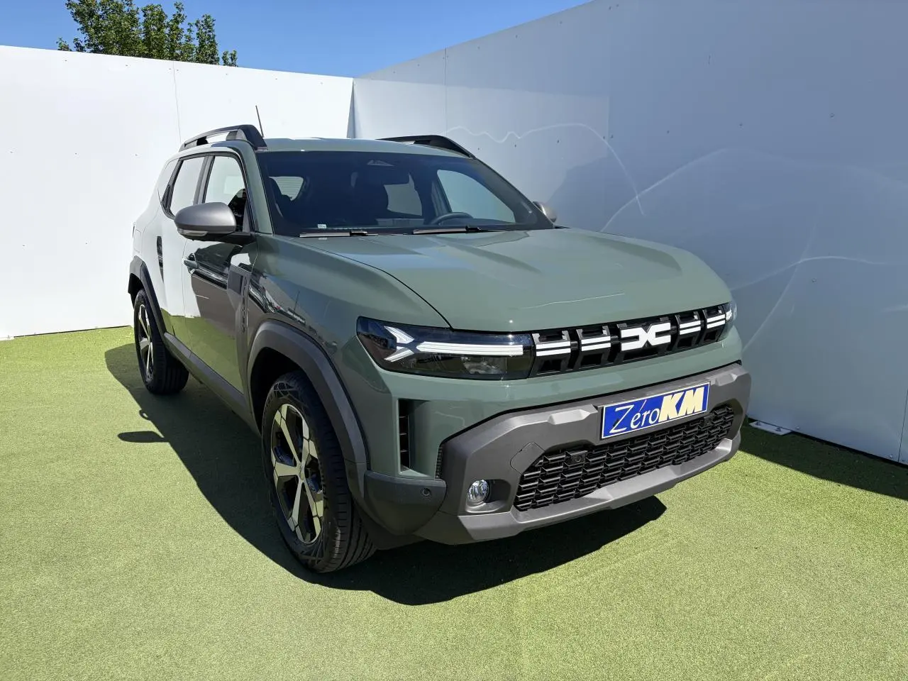 Vue 3/4 avant d'un Dacia Duster III hybride kaki lichen avec calandre distinctive et jantes alliage 18 pouces.