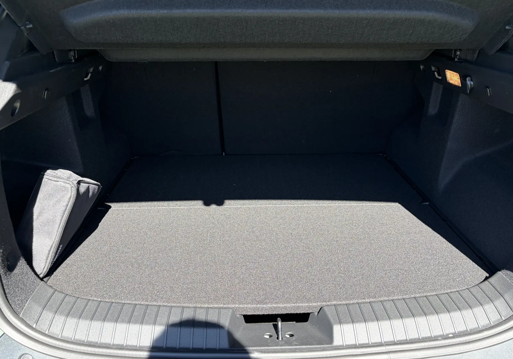 Coffre ouvert vu de face du Dacia Duster III 1.8 Hybrid 155 en kaki lichen, espace de chargement vide et propre.
