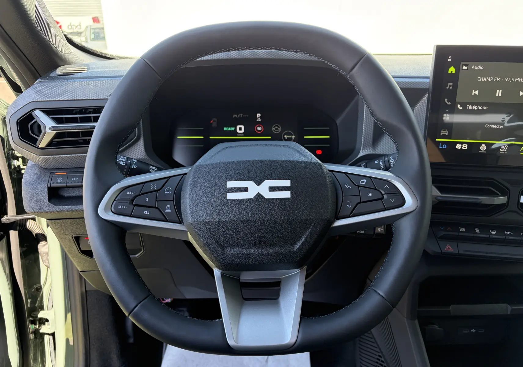 Vue intérieure centrée sur le volant noir du Dacia Duster III 2026 avec tableau de bord digital et écran tactile.