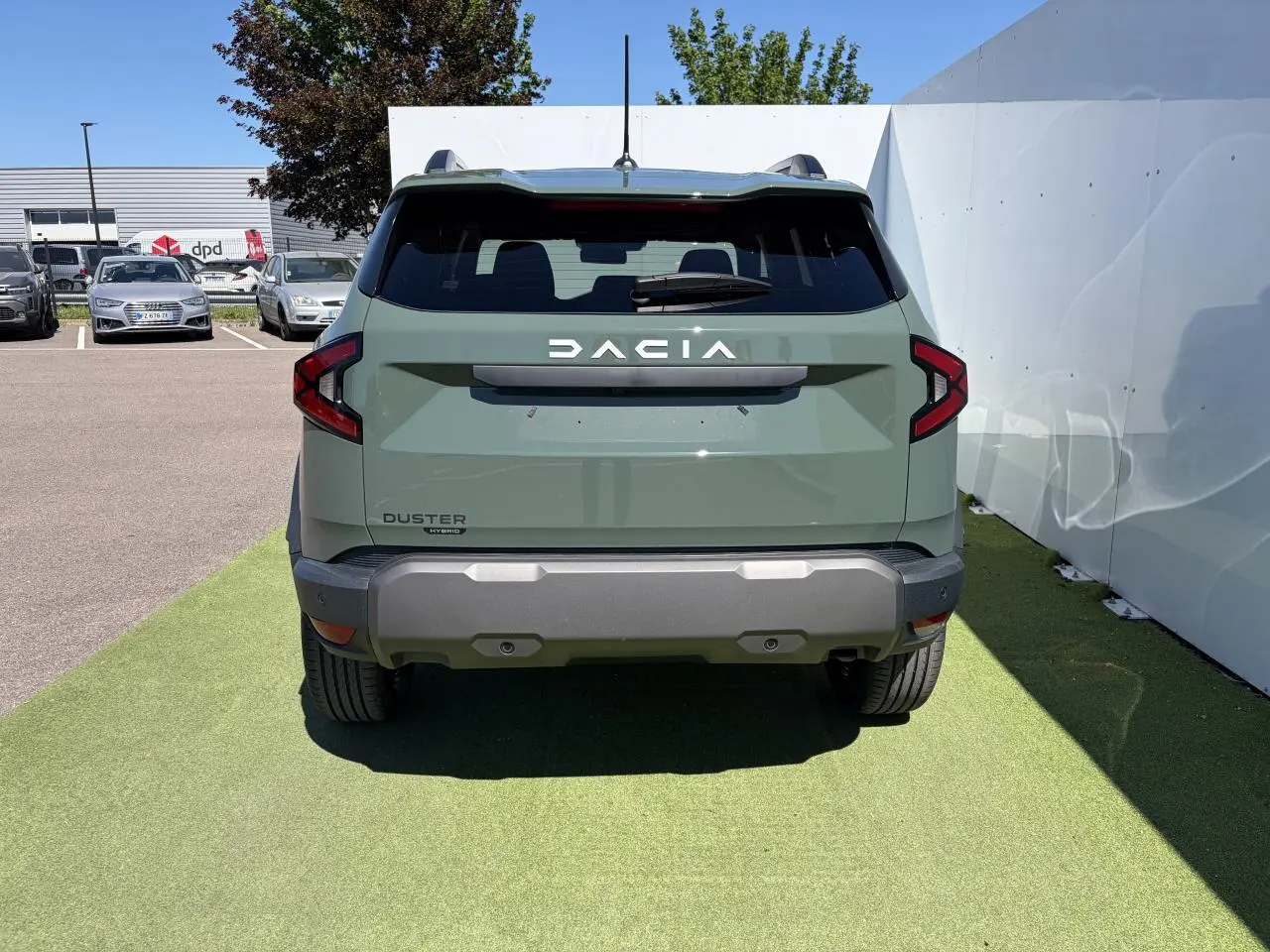 Vue arrière d'un Dacia Duster III hybride 2026 en kaki lichen avec feux arrière LED et pare-chocs gris.