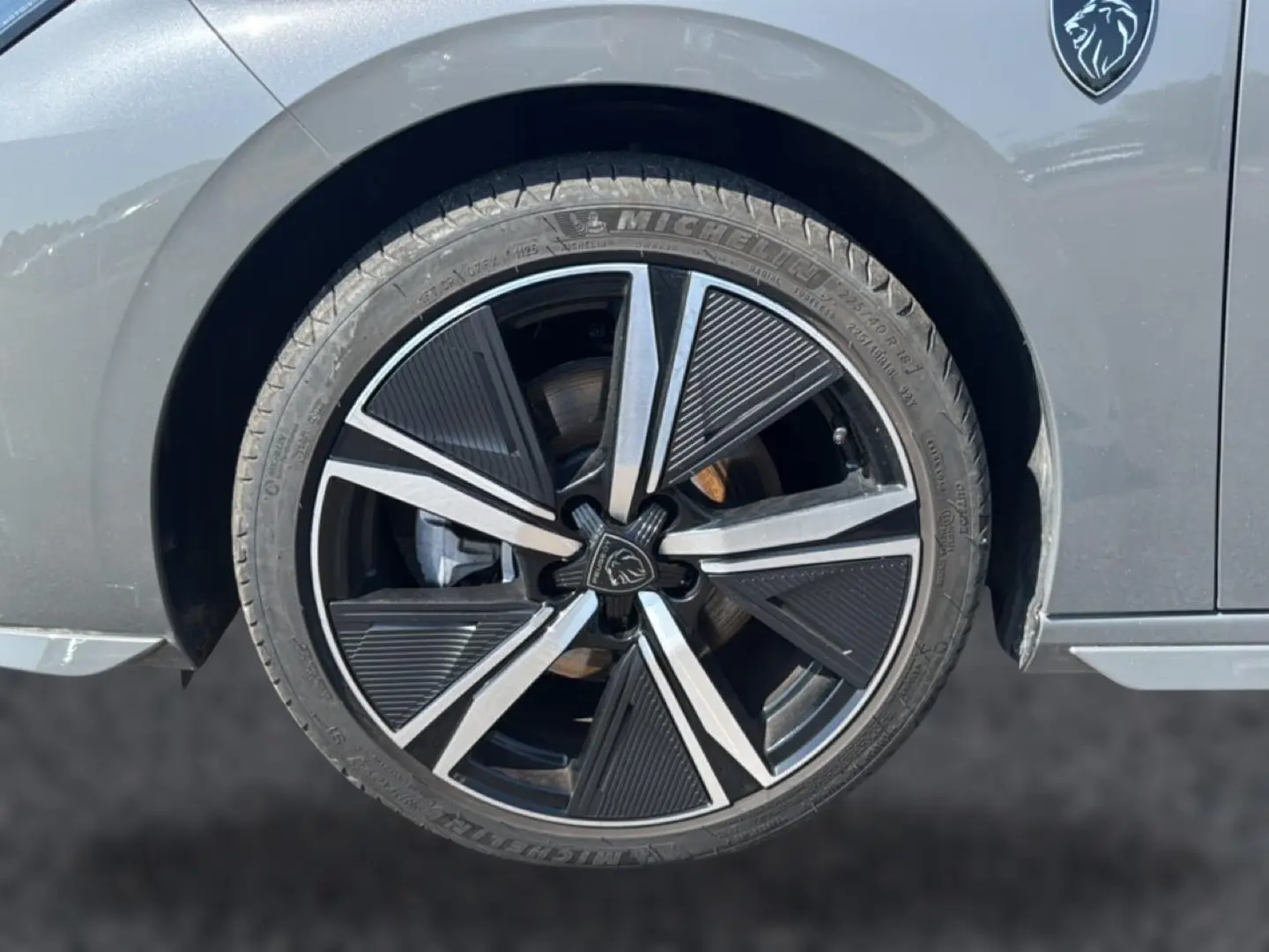 Gros plan sur la roue avant droite grise d’une Peugeot 308 1.2 hybrid 145 GT avec jante alu noire et argentée.