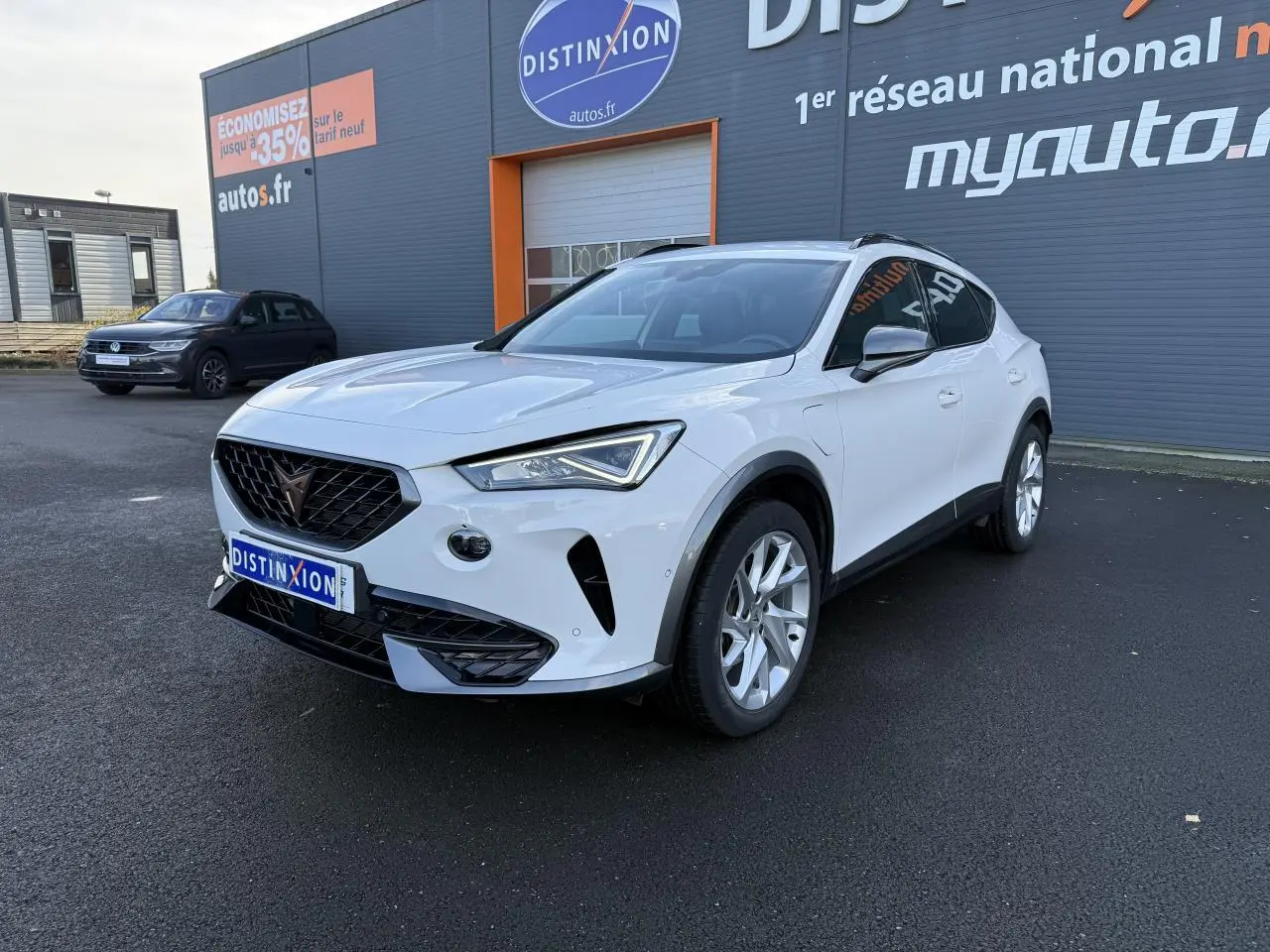 Vue 3/4 avant d'un CUPRA Formentor blanc 2023 hybride rechargeable, avec jantes alliage et calandre noire distinctive.