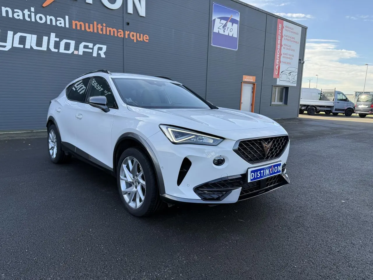 Vue 3/4 avant d'un CUPRA Formentor blanc hybride rechargeable, avec jantes alliage 18'' et calandre noire distinctive.