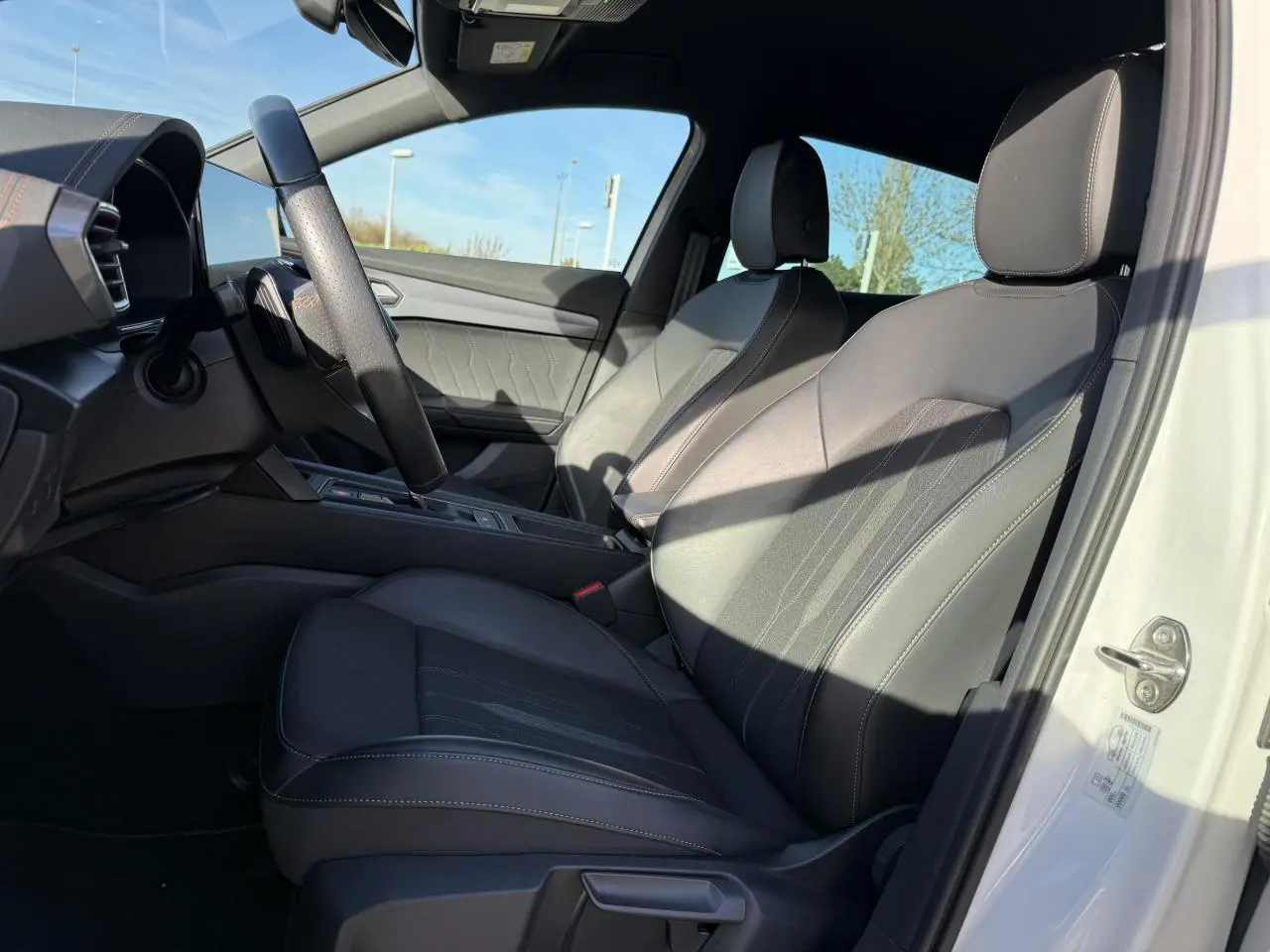 Vue intérieure côté conducteur du CUPRA Formentor blanc 2023, sièges en cuir noir avec surpiqûres contrastées.