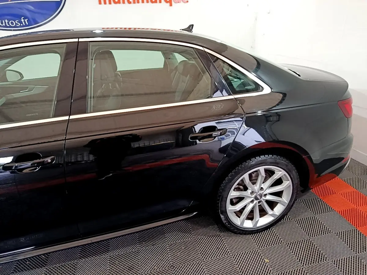 Vue latérale côté droit de l'Audi A4 noire 40 TDI 190 Quat S tronic Design Luxe, mettant en valeur la jante alliage et les lignes élégantes.