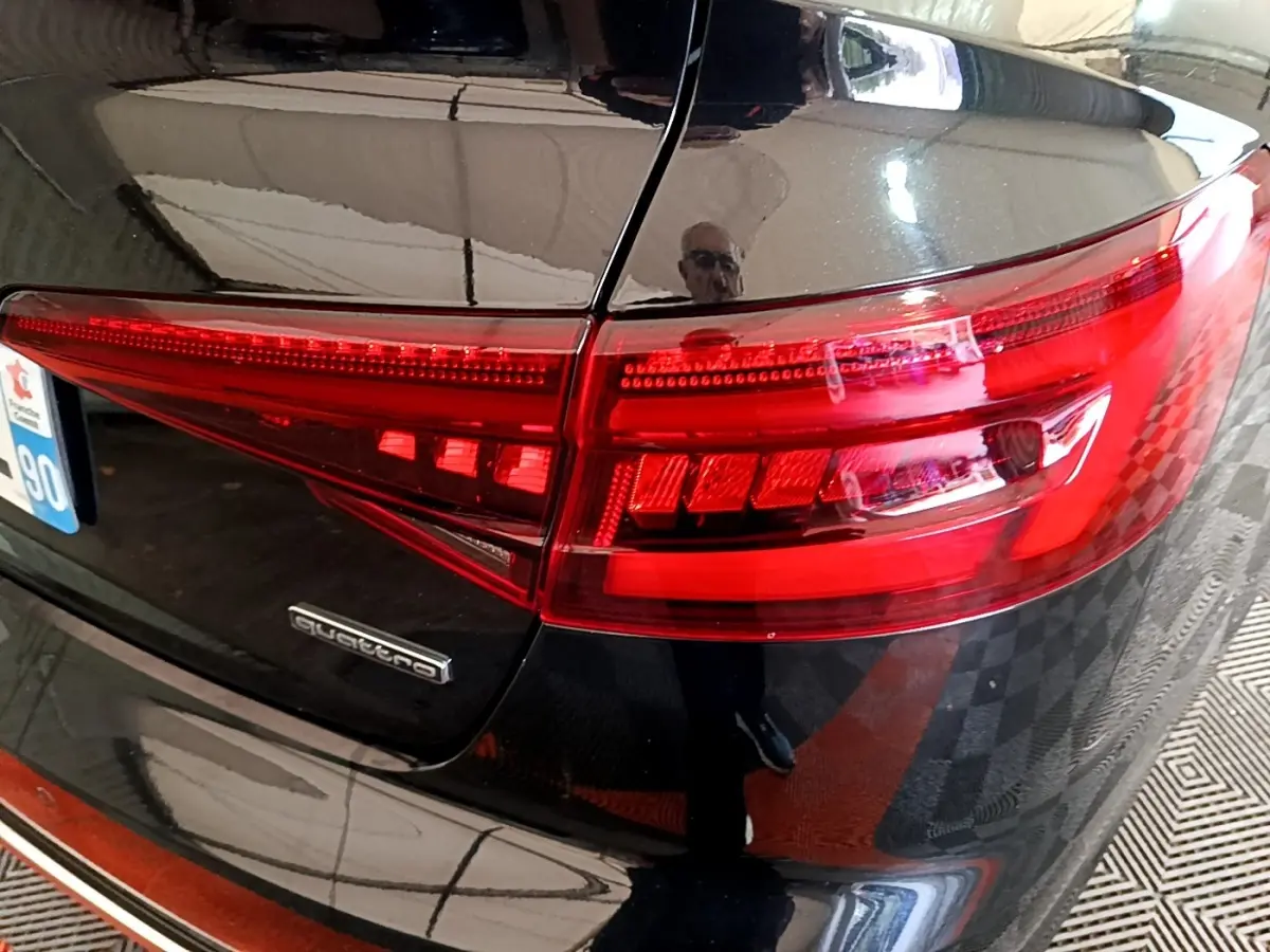 Gros plan sur le feu arrière droit rouge et la carrosserie noire brillante d'une Audi A4 40 TDI Quattro de 2018.