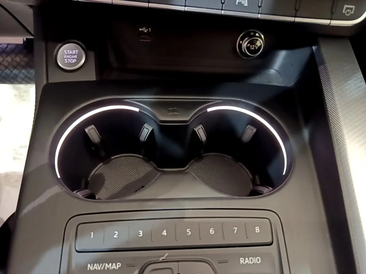 Gros plan sur la console centrale noire de l'Audi A4 40 TDI 2018, avec porte-gobelets éclairés et bouton démarrage visible.