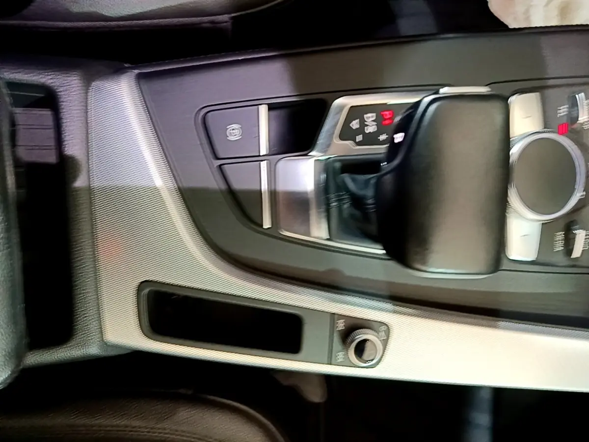 Gros plan sur la console centrale noire et argentée de l'Audi A4 40 TDI 190 Quat S tronic Design Luxe avec levier de vitesse automatique.