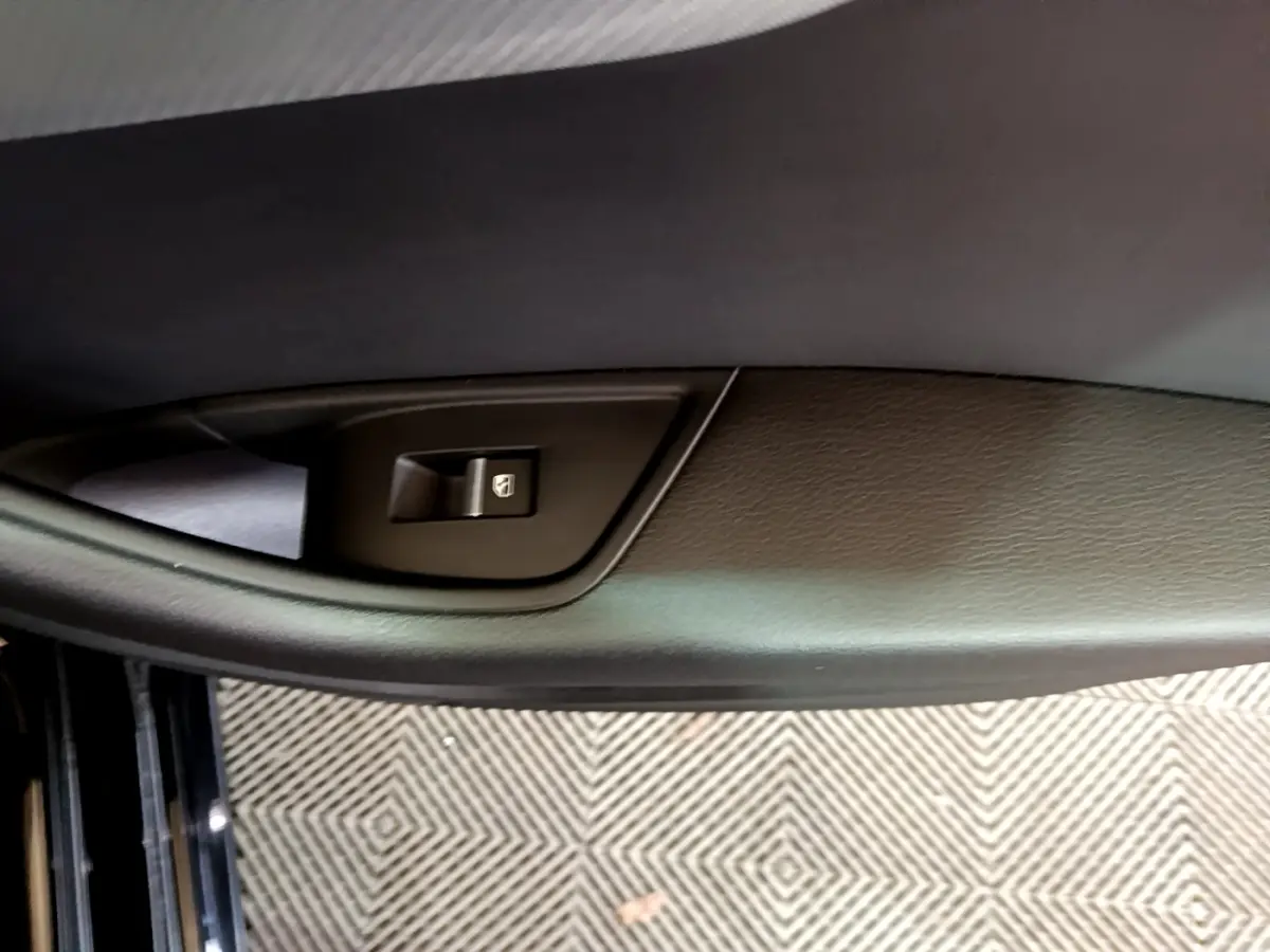 Gros plan sur la commande de lève-vitre côté conducteur d'une Audi A4 noire, intérieur cuir noir.