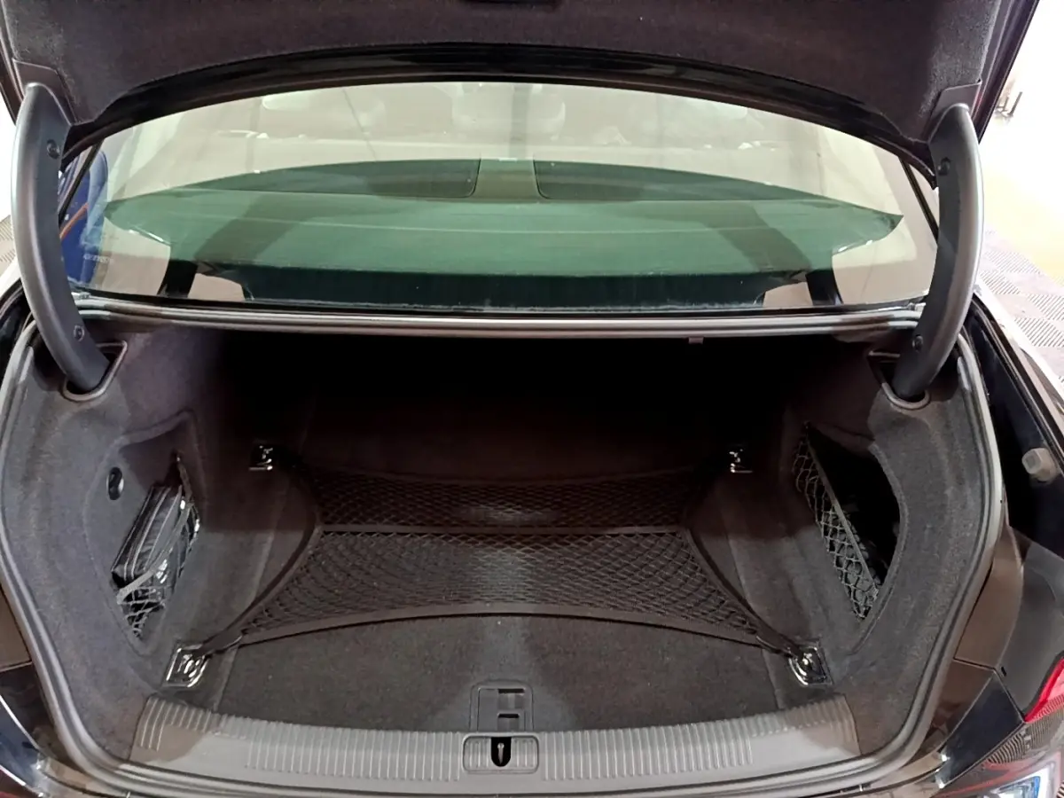 Vue du coffre ouvert de l'Audi A4 noire 2018, montrant l'espace de rangement avec filet de maintien et garniture noire.