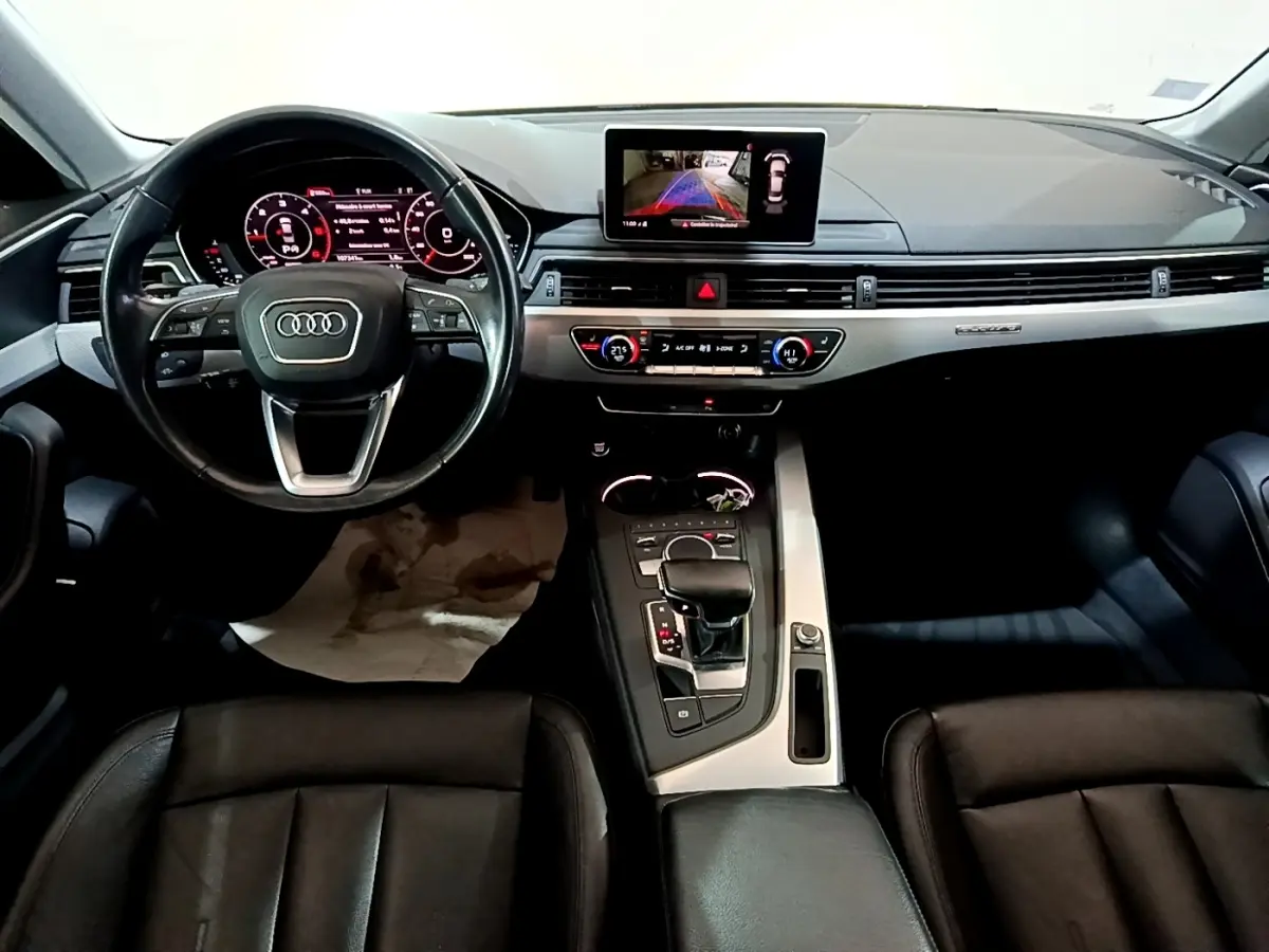 Vue intérieure avant de l'Audi A4 40 TDI noire, tableau de bord moderne avec écran tactile et volant cuir multifonctions.