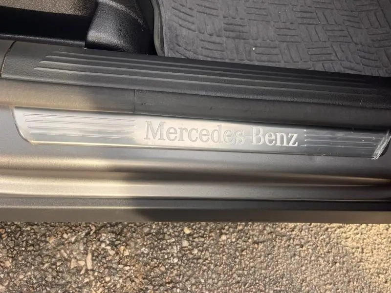 Gros plan sur la plaque de seuil de porte Mercedes-Benz en métal brossé, sur fond gris montagne mat.