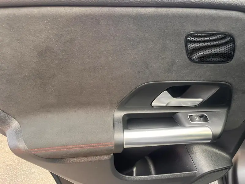 Gros plan sur la porte intérieure côté gauche de la Mercedes GLA 200 d AMG Line 2021 en gris montagne magno avec surpiqûres rouges.