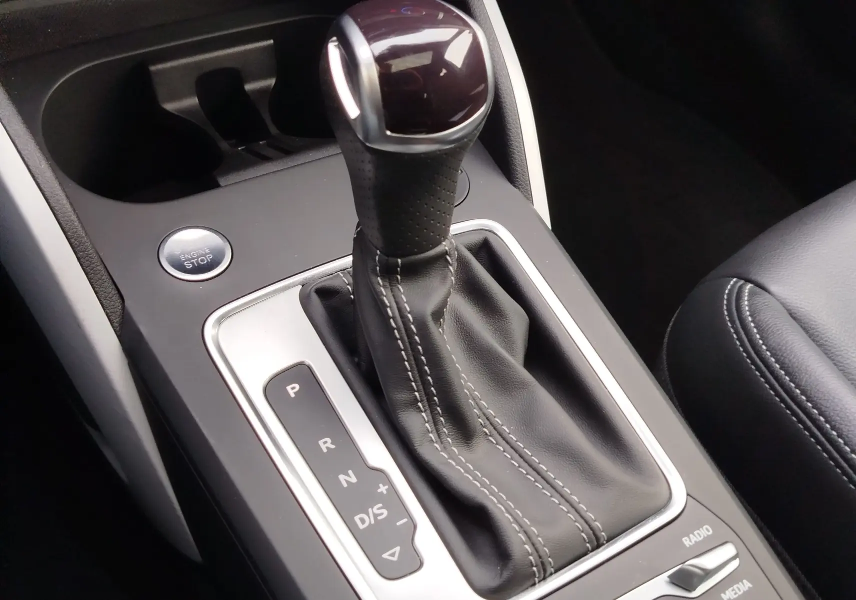 Gros plan sur le levier de vitesses automatique en cuir noir et bouton start/stop de l’Audi Q2 35 TFSI 2023.