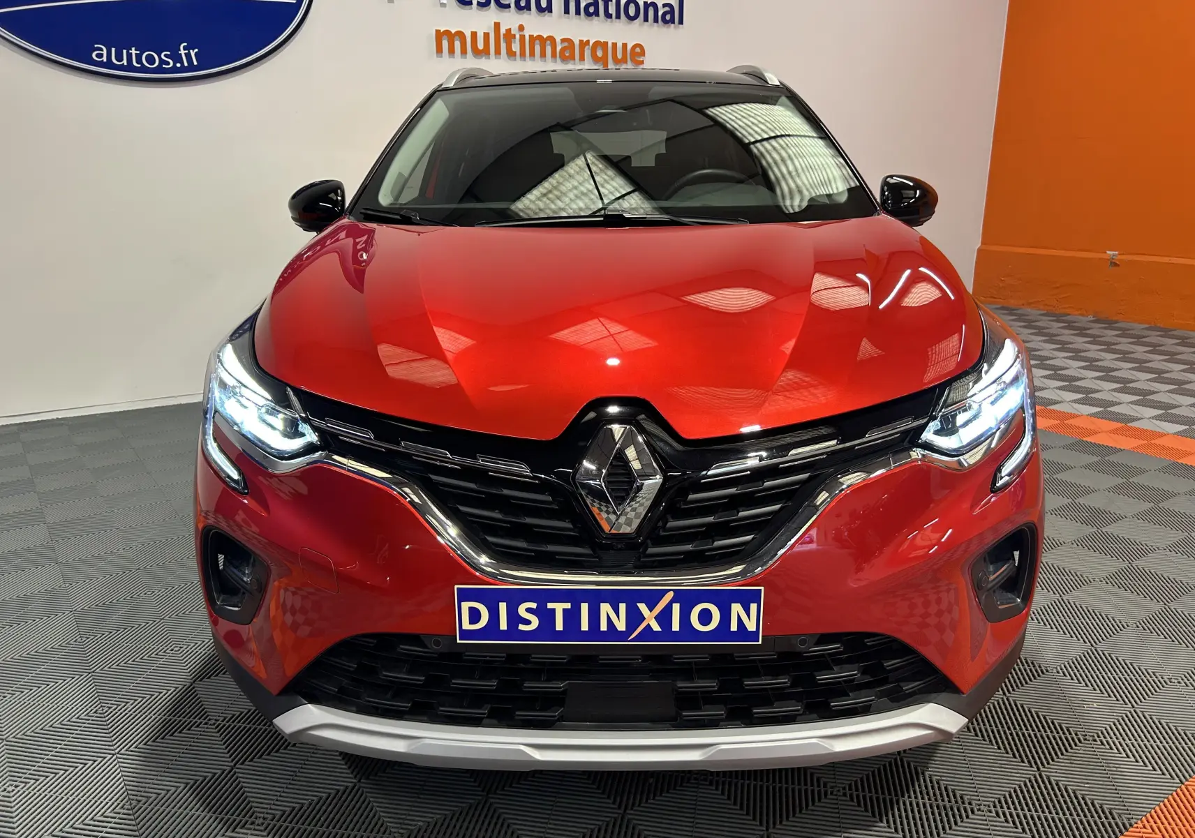 Vue avant d'un Renault Captur 2024 rouge flamme métal avec phares LED allumés et calandre chromée.