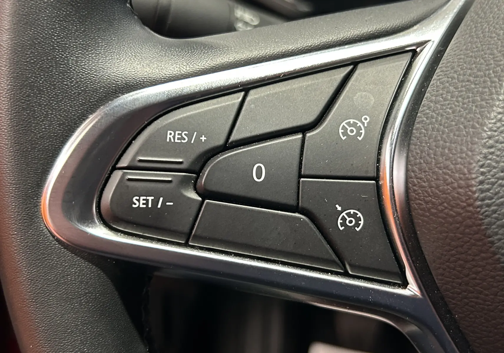 Gros plan sur les commandes de régulateur de vitesse au volant du Renault Captur rouge flamme métal 2024.