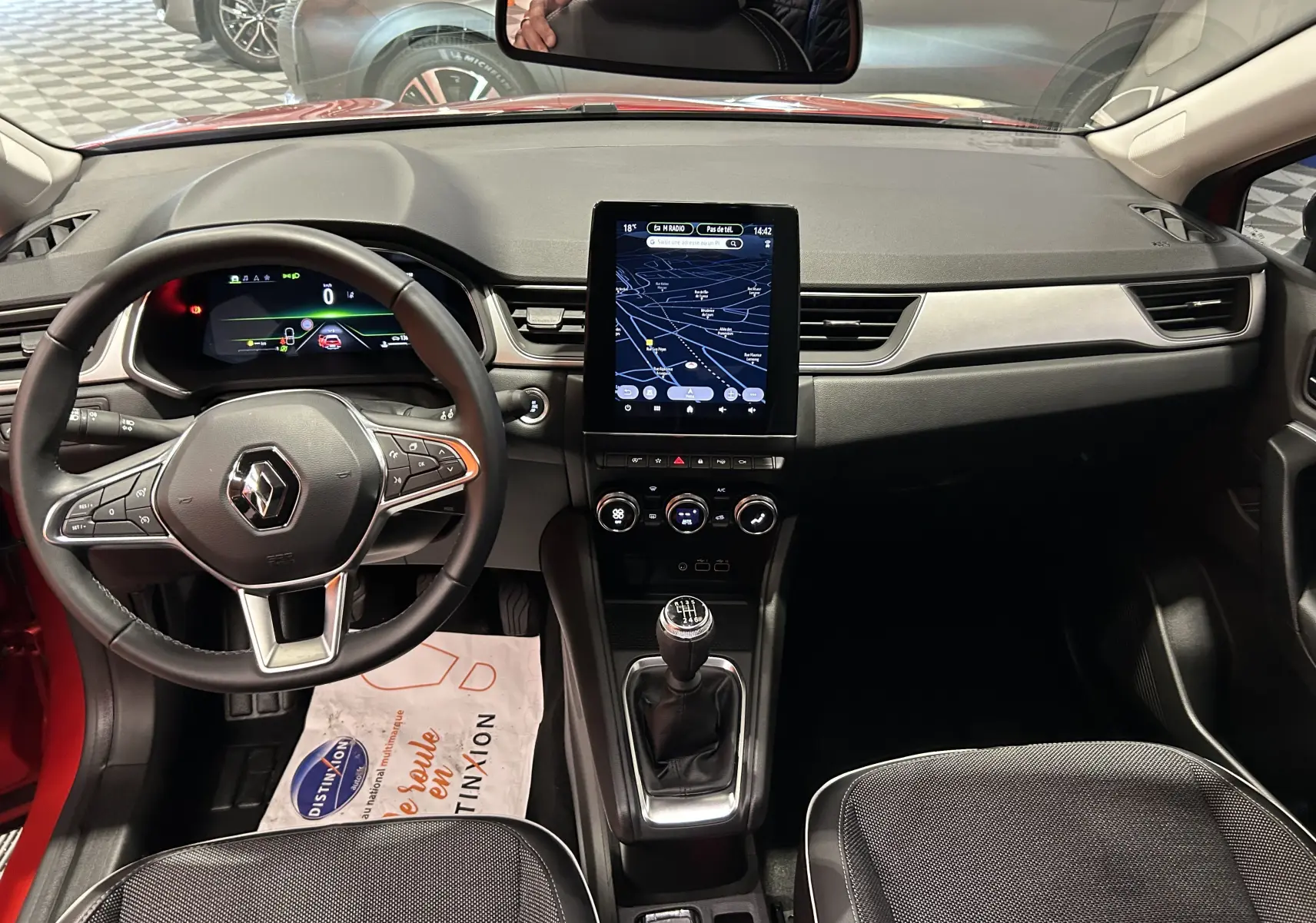 Vue intérieure avant du Renault Captur rouge flamme métal 2024, avec tableau de bord numérique et écran tactile vertical.