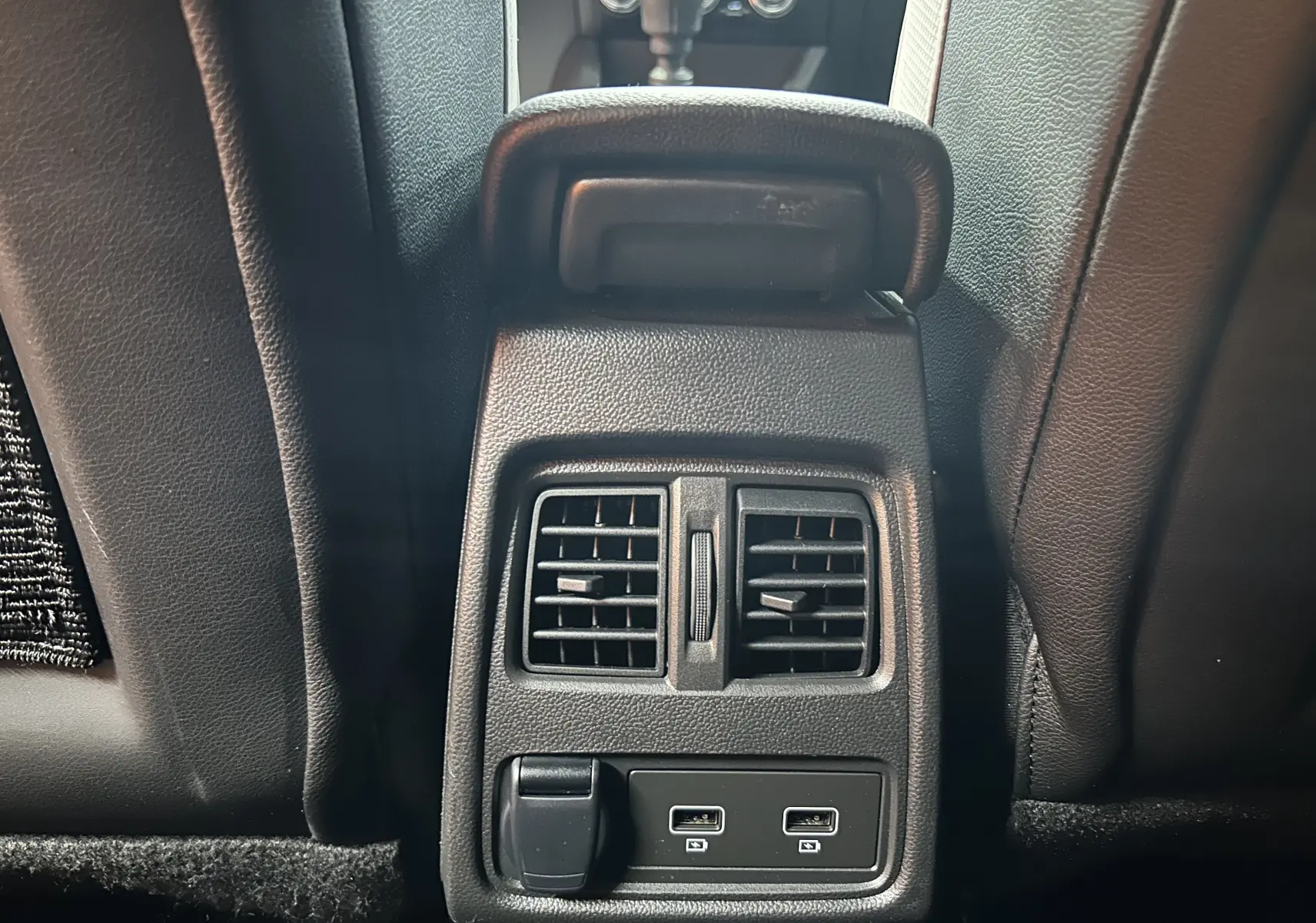 Vue rapprochée des aérateurs arrière et ports USB du Renault Captur TCE 90CH TECHNO rouge flamme métal, intérieur noir cuir.