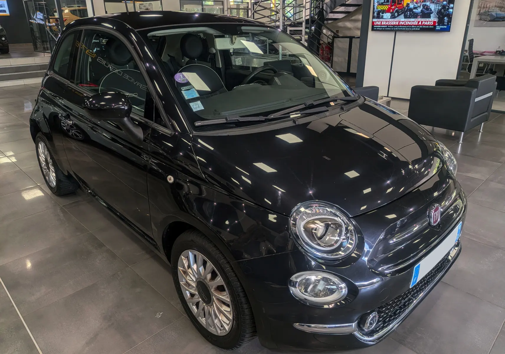 Fiat 500 1.2 69 CH Lounge noire vue en 3/4 avant droit dans un showroom avec reflets au plafond.
