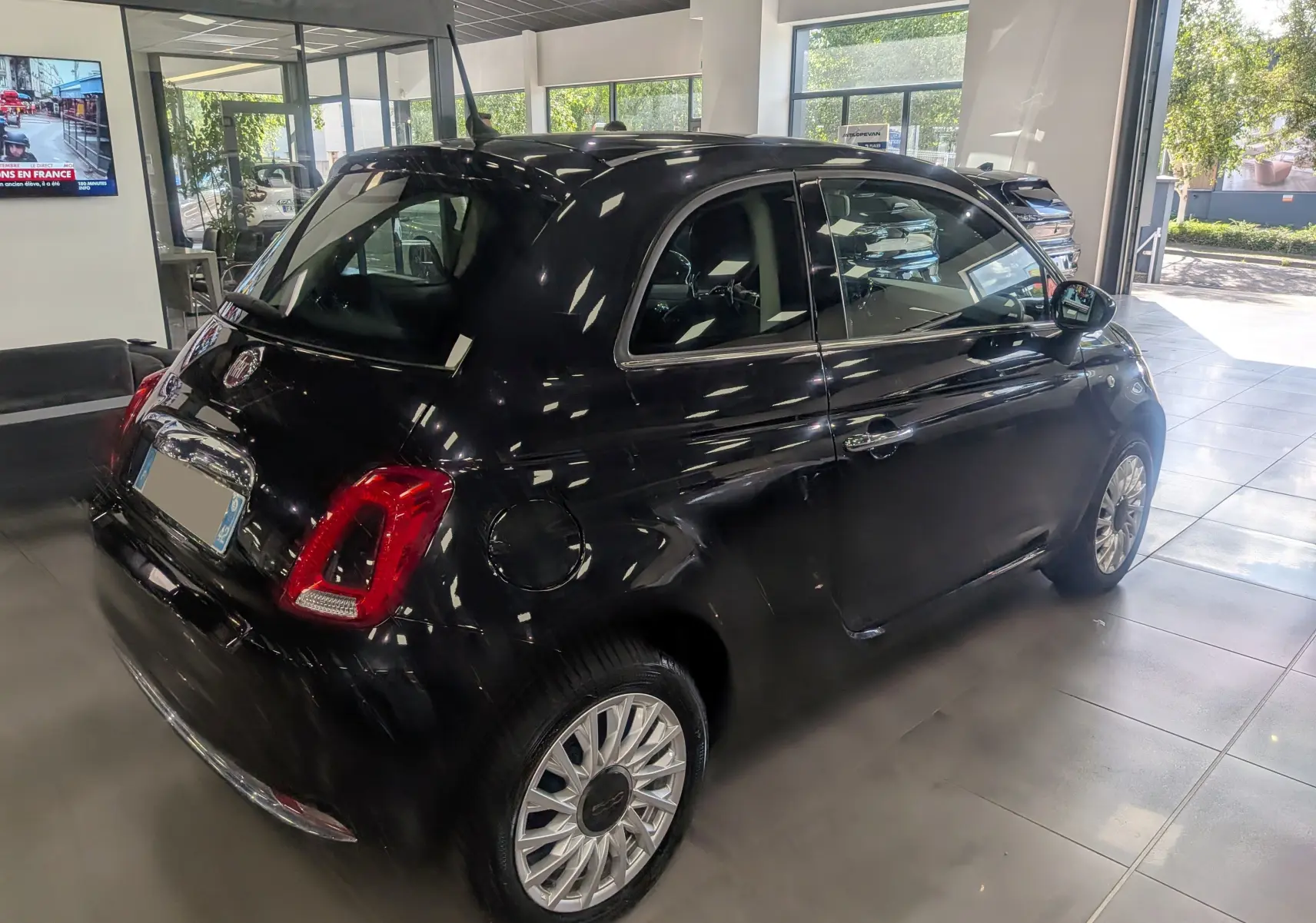 Fiat 500 1.2 69 CH Lounge noire vue 3/4 arrière droit en intérieur avec jantes alliage et feux arrière rouges.