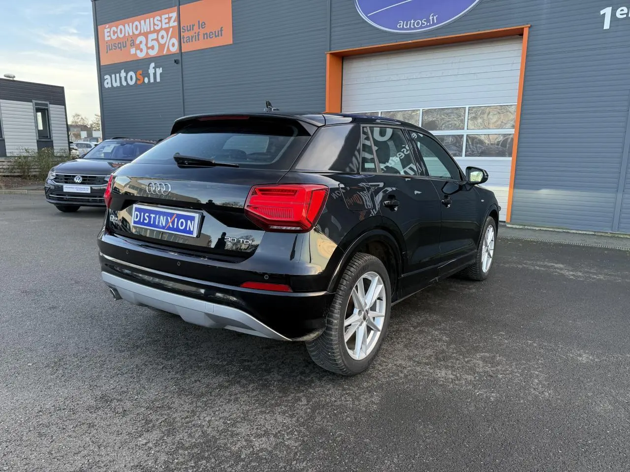 Audi Q2 noir brillant vue 3/4 arrière droit, avec badge 30 TDI et jantes alliage visibles sur un parking extérieur.