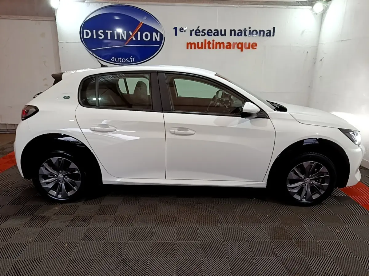 Profil côté gauche d'une Peugeot 208 électrique Active Business blanche, avec jantes alliage et logo e-208 visible.