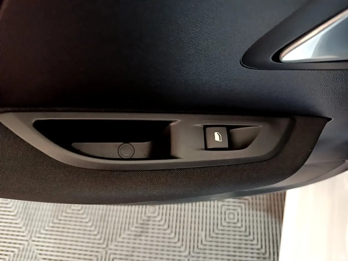 Bouton de verrouillage de porte noir sur panneau intérieur tissu côté conducteur d'une Peugeot 208 blanche électrique 2021.