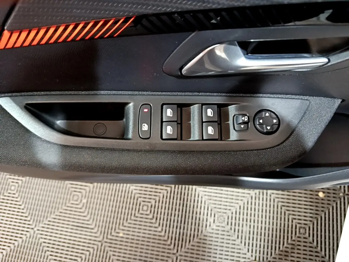 Gros plan sur la commande des vitres et rétroviseurs côté conducteur de la Peugeot 208 électrique blanche Active Business.