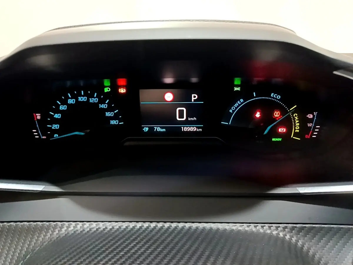 Tableau de bord numérique de la Peugeot 208 électrique blanche, affichant vitesse, autonomie et indicateurs énergie.