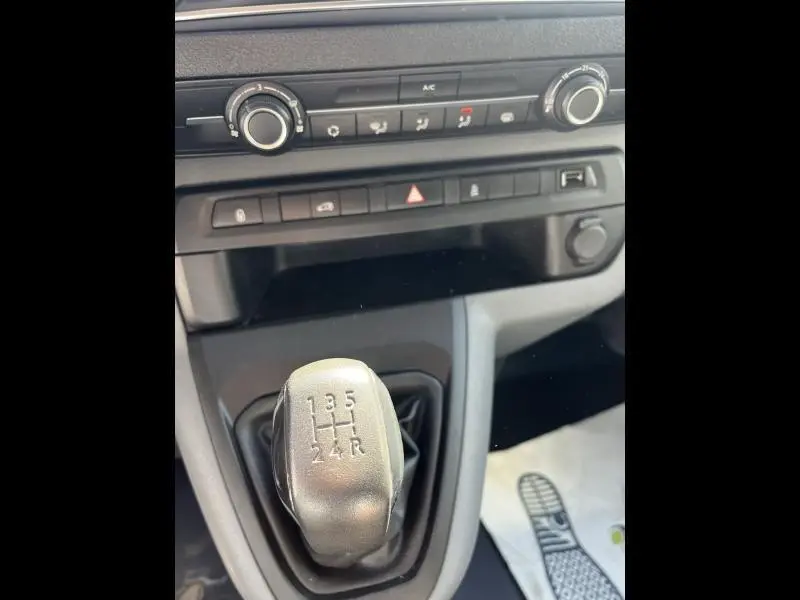 Gros plan sur le levier de vitesses manuel gris du Citroën Jumpy blanc, avec commandes de climatisation en arrière-plan.