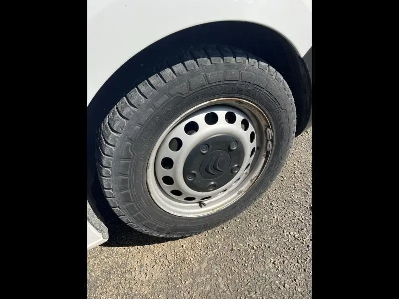 Gros plan sur la roue avant droite d'un Citroën Jumpy blanc Banquise avec jante tôle grise et logo Citroën central.