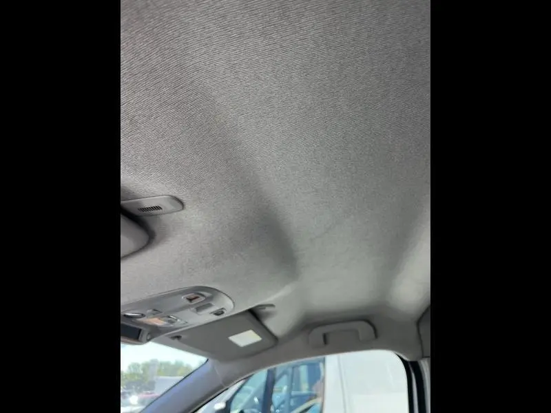 Plafond intérieur gris clair du Citroën Jumpy blanc Banquise, avec pare-soleil et éclairage au-dessus du siège conducteur.