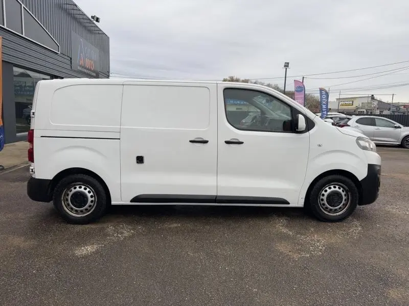Vue de profil côté gauche d’un utilitaire Citroën Jumpy blanc Banquise avec porte latérale coulissante et jantes tôle grises.