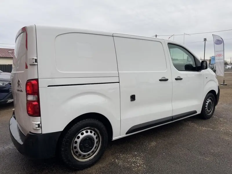 Vue 3/4 arrière droite d'un Citroën Jumpy blanc Banquise avec portes latérales et jantes tôles grises.