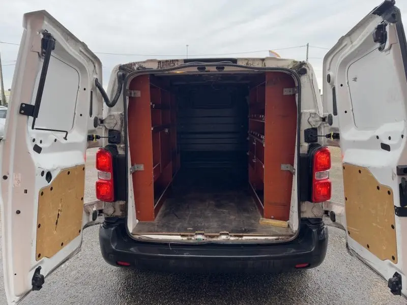 Vue arrière d’un Citroën Jumpy blanc Banquise 2018 avec portes arrière ouvertes et aménagements bois dans l’espace de chargement.