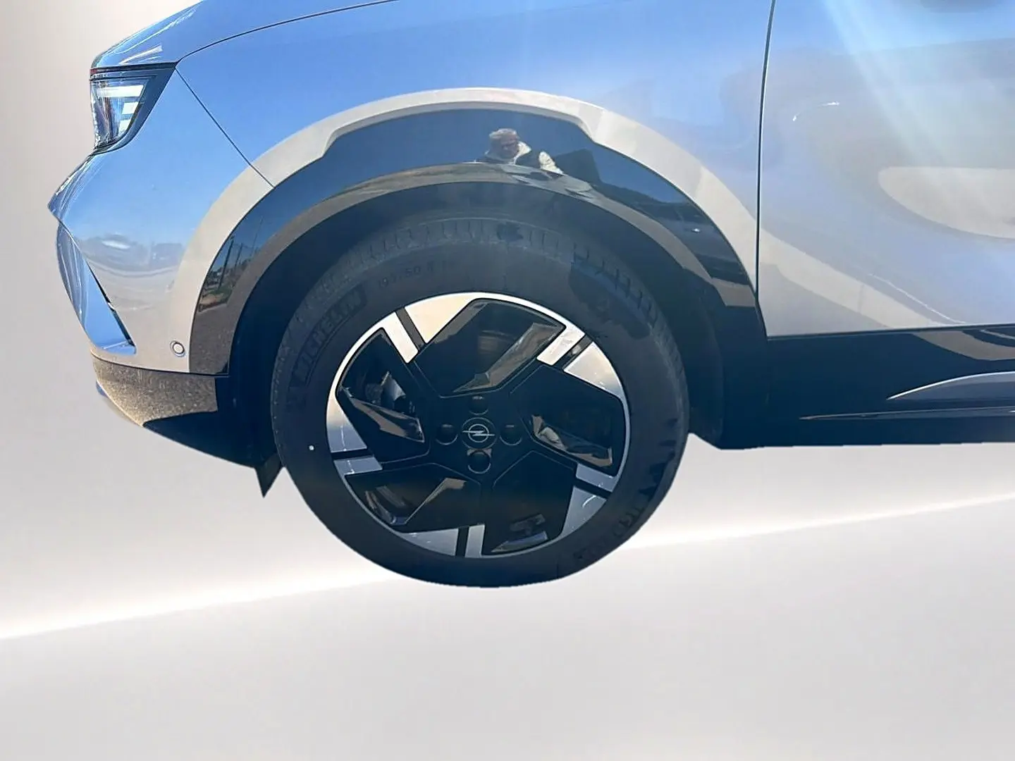Gros plan sur la roue avant gauche et la partie basse grise d’un Opel Mokka Electric 156 gs avec jante alu noire et argent.