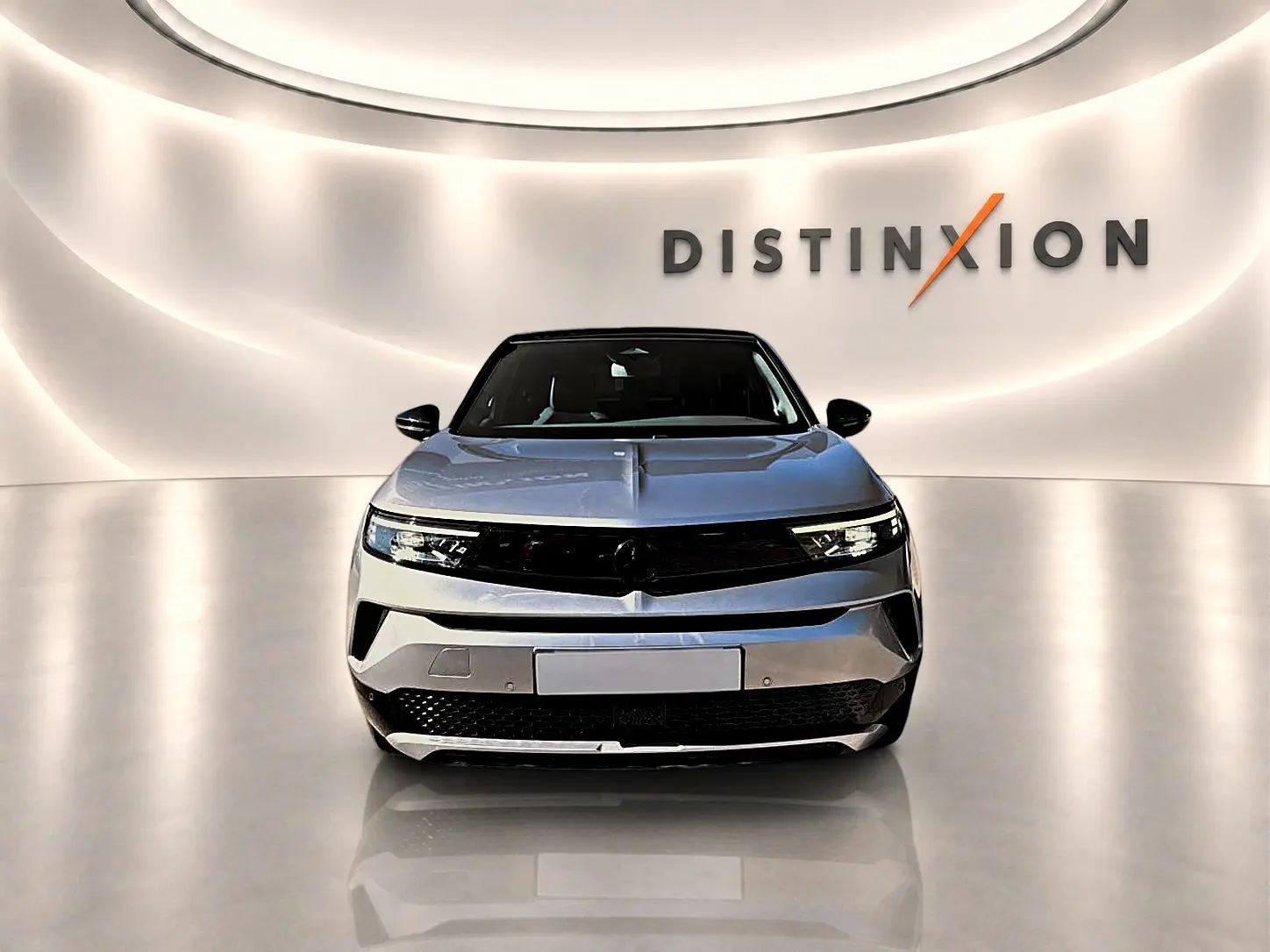 Vue frontale d'un Opel Mokka Electric 156 GS gris, avec calandre noire et éclairage LED moderne dans un showroom épuré.