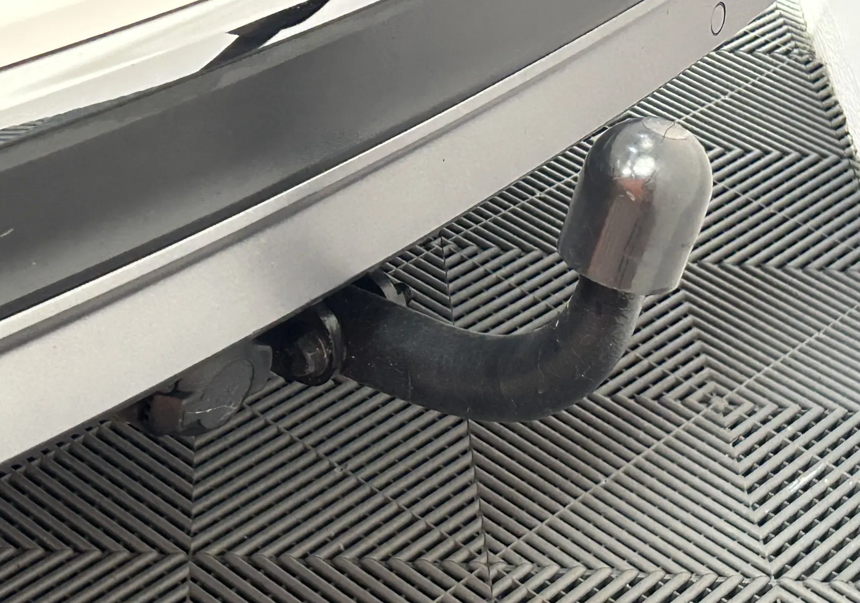 Gros plan sur l'attelage noir fixé à l'arrière blanc du Volkswagen Tiguan Allspace 2018, sur sol en damier.