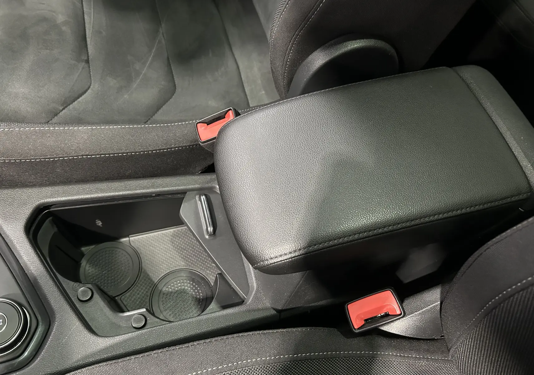 Gros plan sur la console centrale noire avec accoudoir et porte-gobelets du Volkswagen Tiguan Allspace 2018.