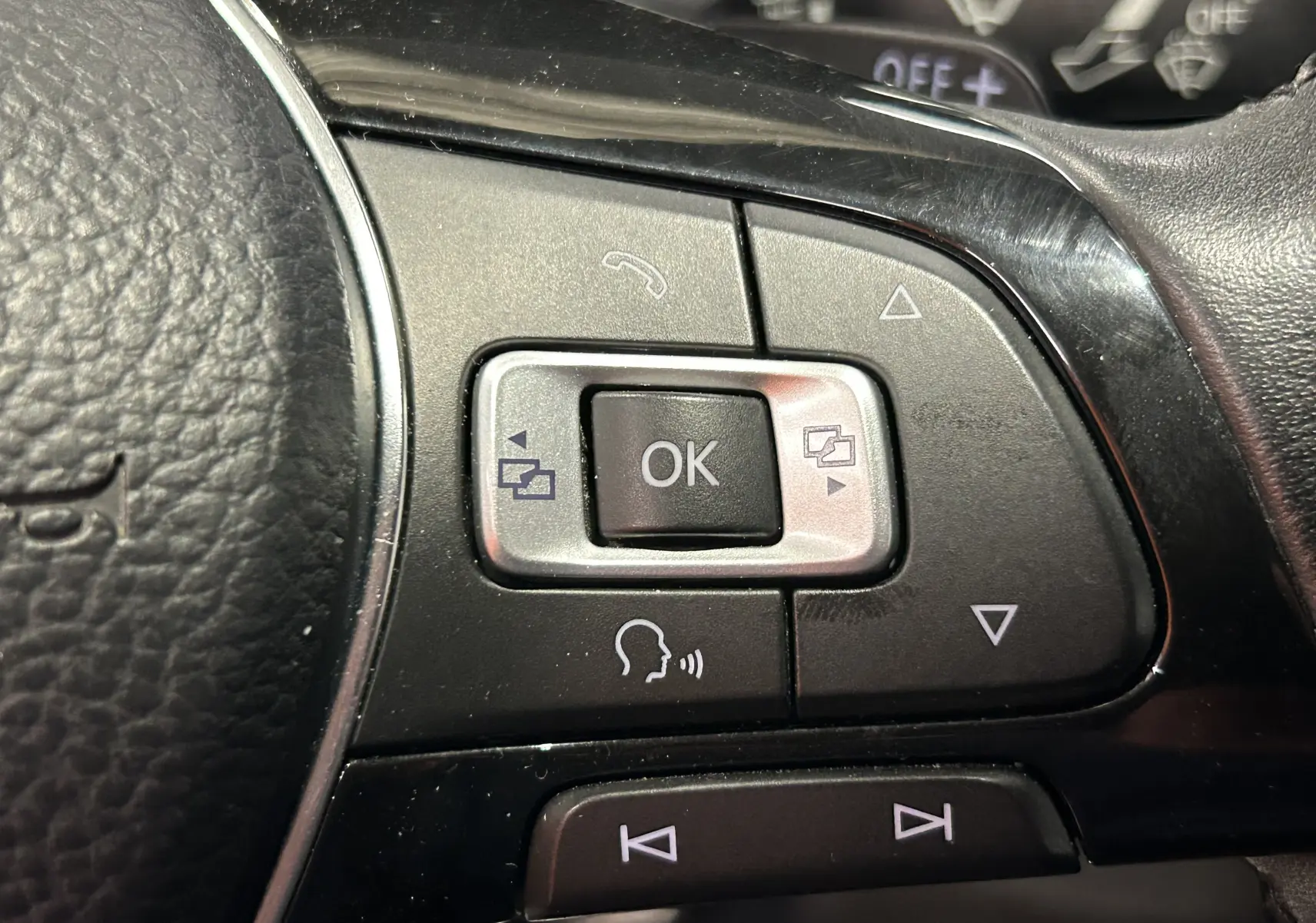 Gros plan sur les commandes multifonctions noires du volant du Volkswagen Tiguan Allspace blanc, version 2018.