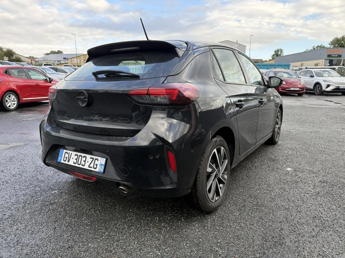 Opel Corsa noire vue 3/4 arrière droit, avec jantes alliage 16 pouces et spoiler arrière sportif.