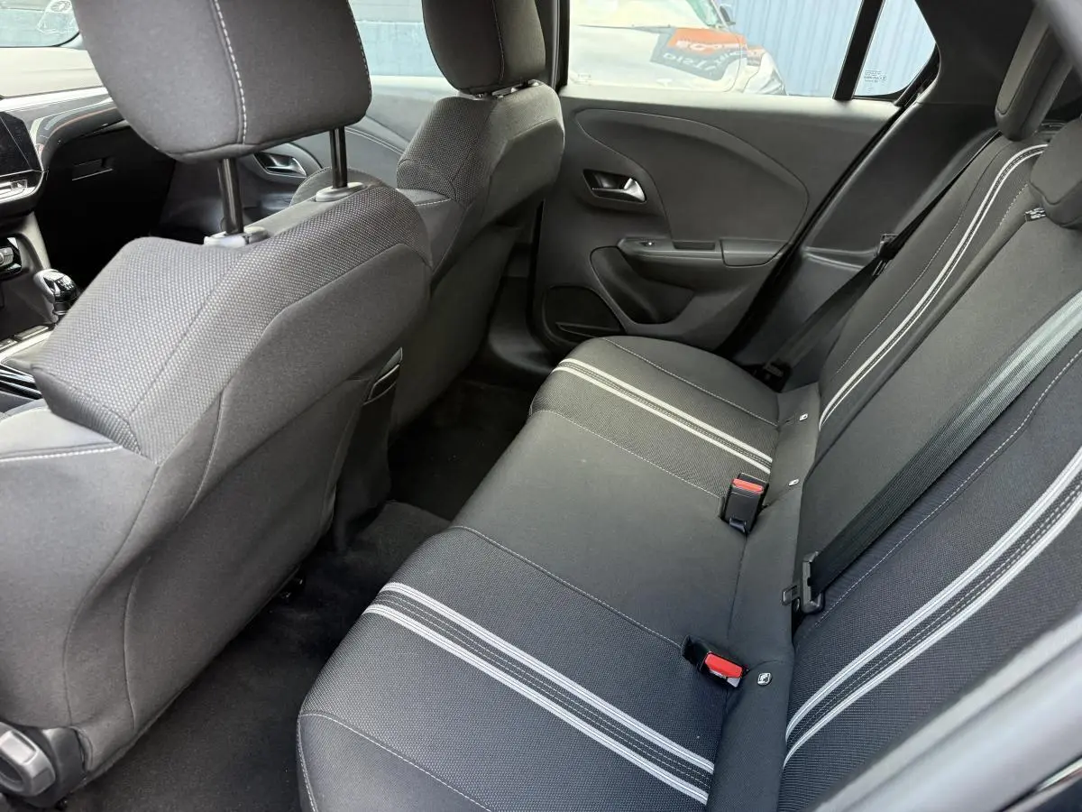 Vue intérieure arrière côté droit de l'Opel Corsa 2024 noire, banquette tissu noir à bandes blanches et appuie-têtes réglables.